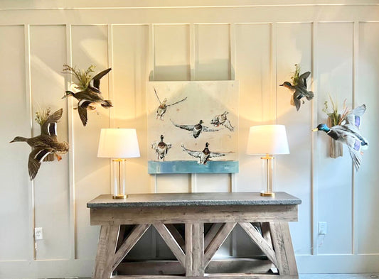Duck canvas print featuring artwork by Chelsea McShane displayed above a side table in an entryway with two lamps. 
